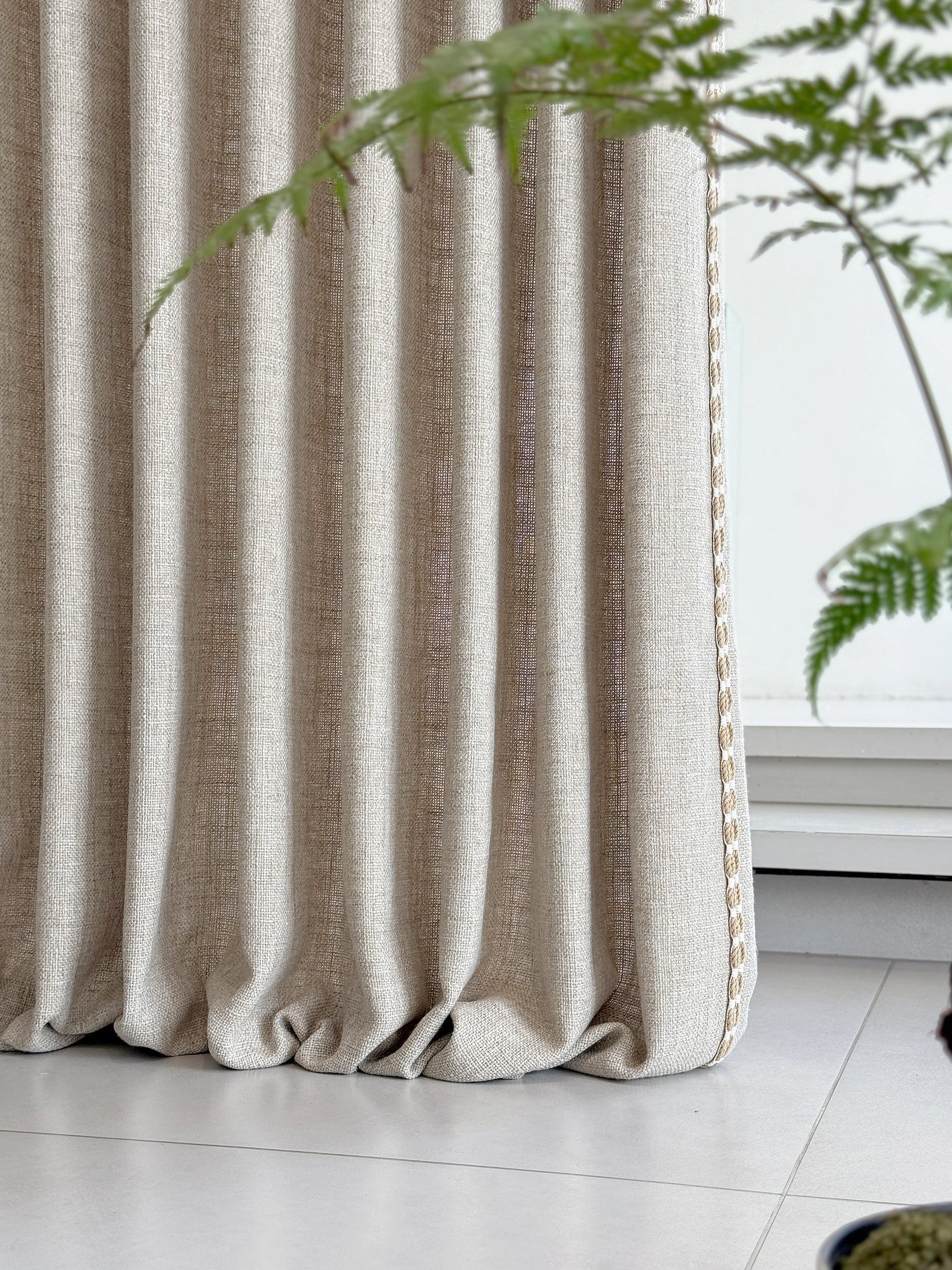 Warm neutral curtain fabric pooling softly in a bright interior